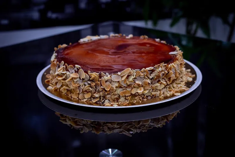Tarta redonda cubierta de almendra laminada reflejada sobre una superficie negra