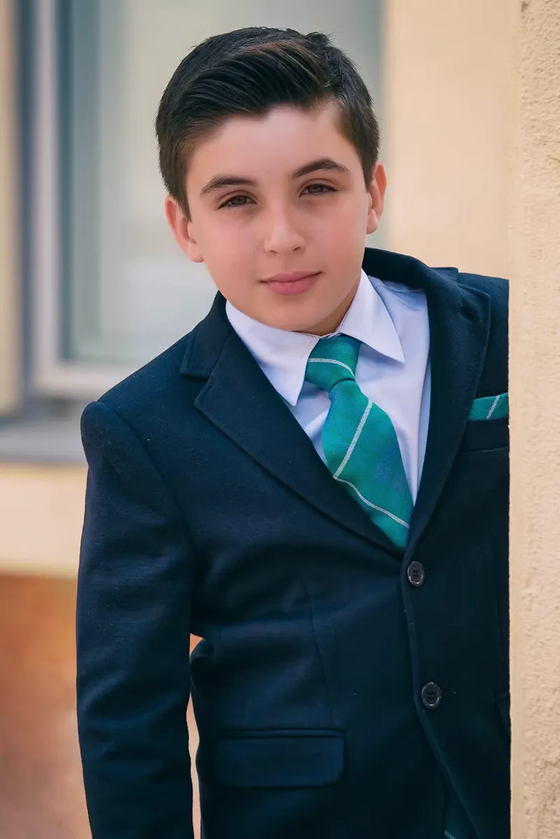 Niño de comunión con traje azul marino y corbata verde