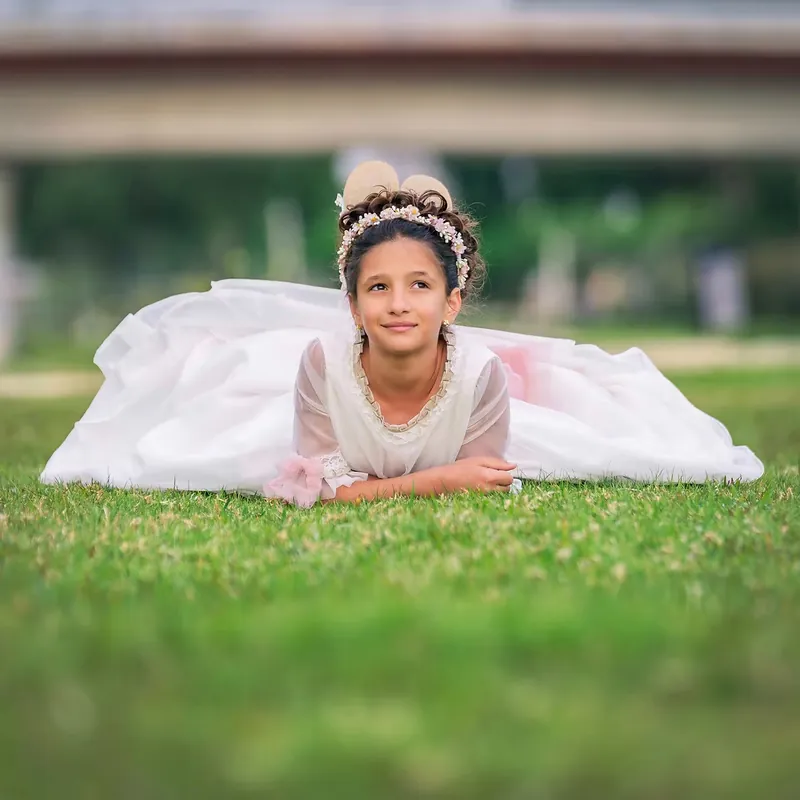 Niña de comunión tumbada sobre el césped con el vestido extendido