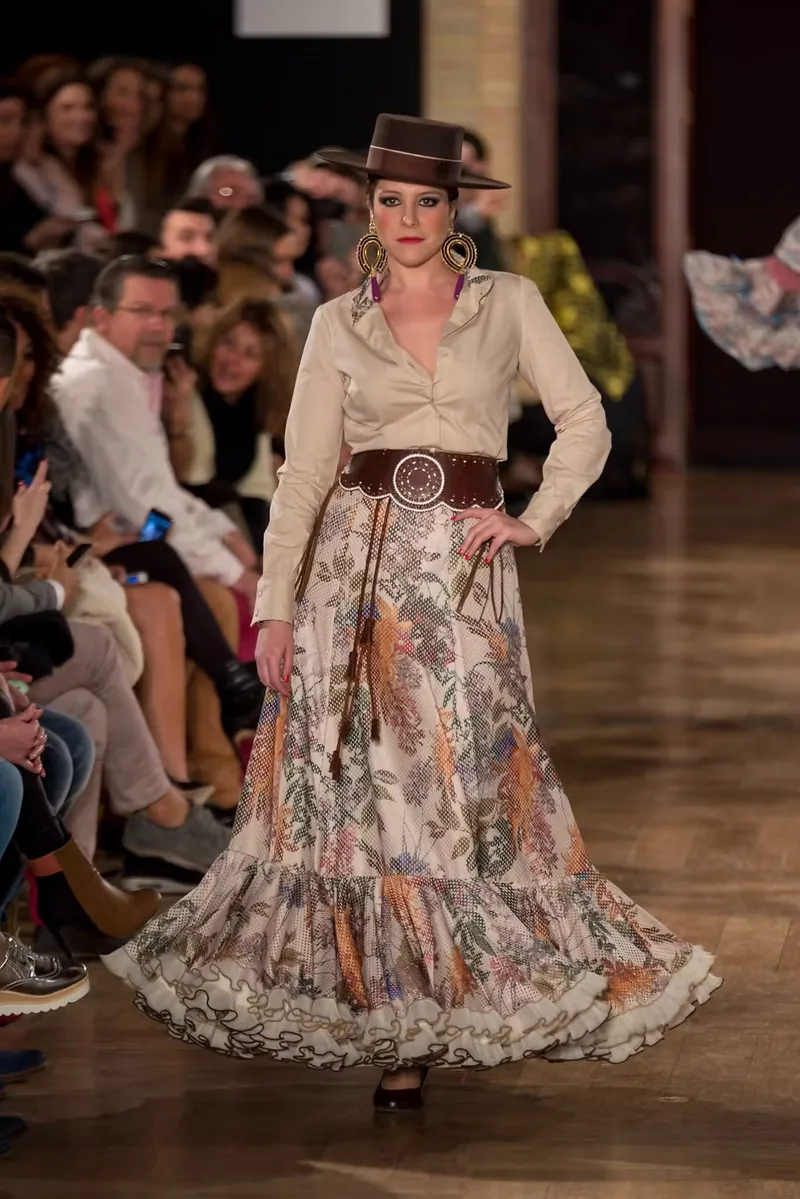 Modelo con falda de volantes y sombrero de ala ancha en un desfile de moda flamenca