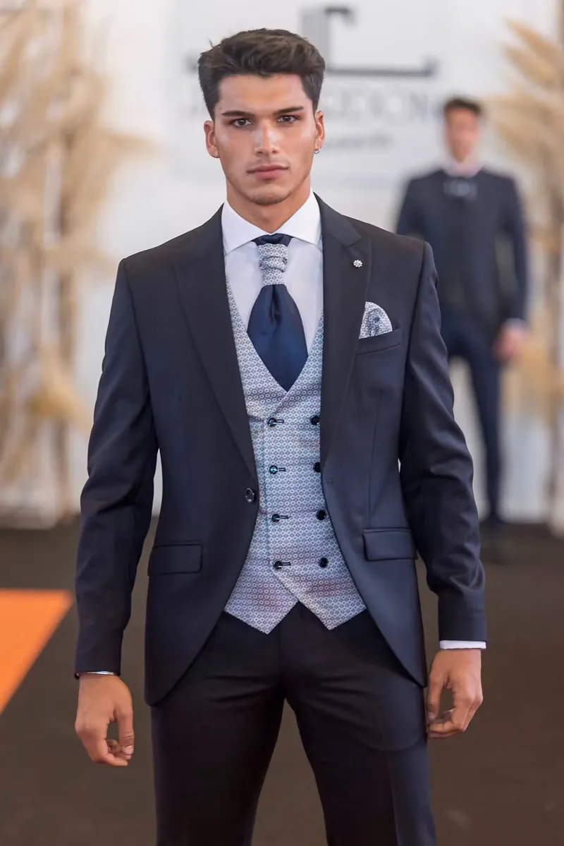 Modelo masculino con traje de ceremonia azul y chaleco en pasarela