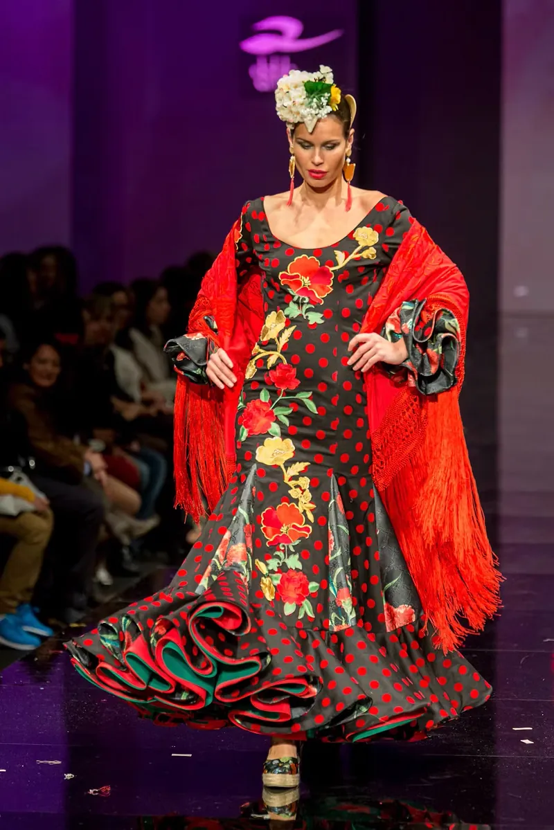 Traje de flamenca con mantón rojo estampado bajo luz escénica morada