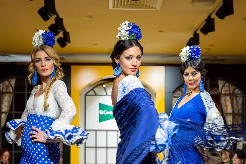 Tres modelos con trajes de flamenca azules y flores en el pelo