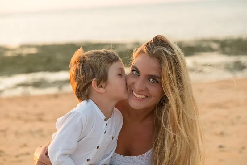 Niño dando un beso a su madre en la playa
