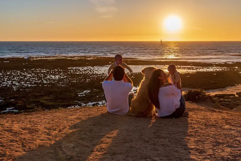 Familia sentada en la orilla viendo la puesta de sol