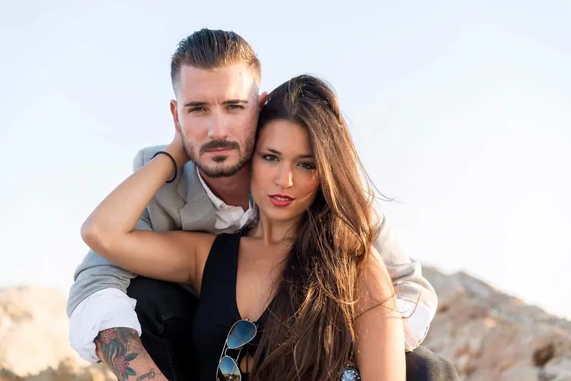 Pareja abrazada entre las rocas de la costa durante una love session