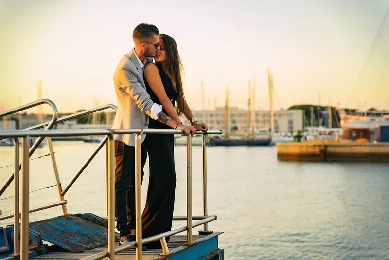 Pareja besándose en la pasarela de un puerto deportivo