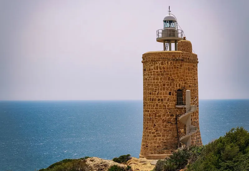 Faro de piedra sobre un acantilado con el mar de fondo