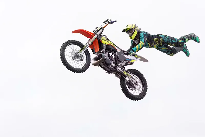 Piloto de motocross freestyle estirado en horizontal sobre la moto en pleno vuelo