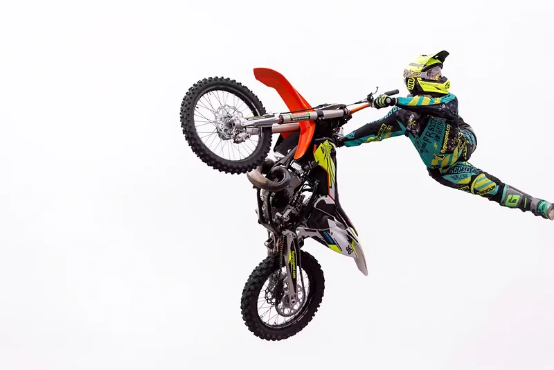 Piloto de motocross freestyle ejecutando un truco vertical en el aire
